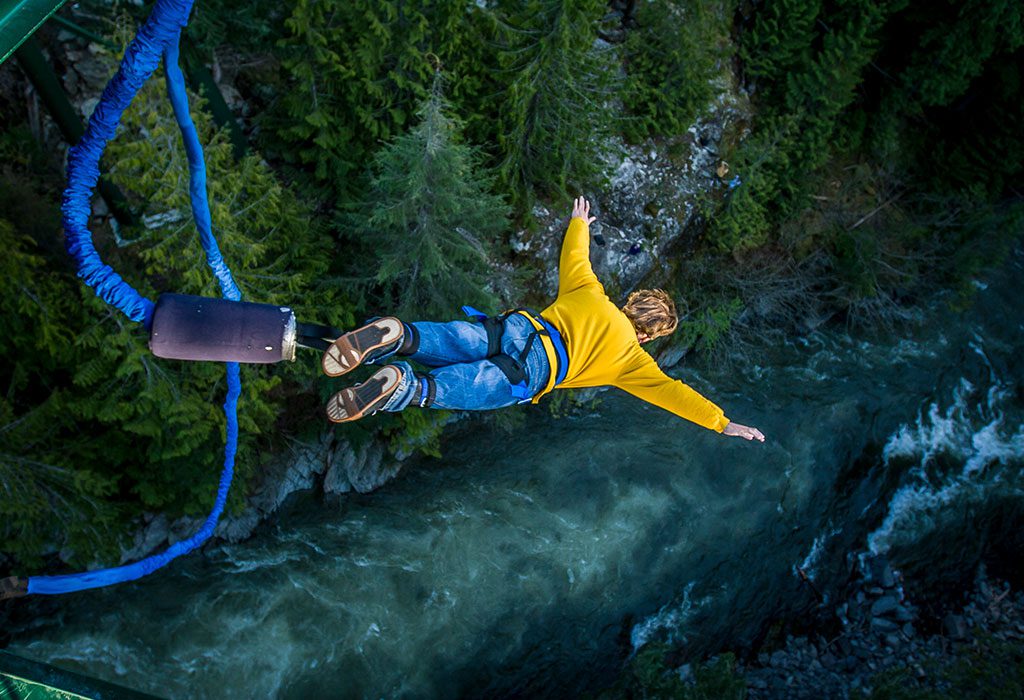 Un hombre práctica la actividad de saltar de un puente en la naturaleza.