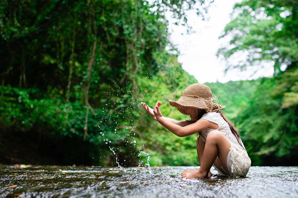 Niña juega en el río.