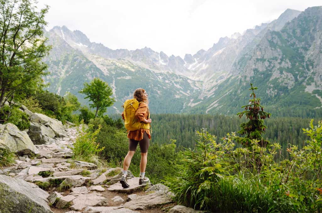 Mujer difruta de las vistas de su ruta por la montaña.
