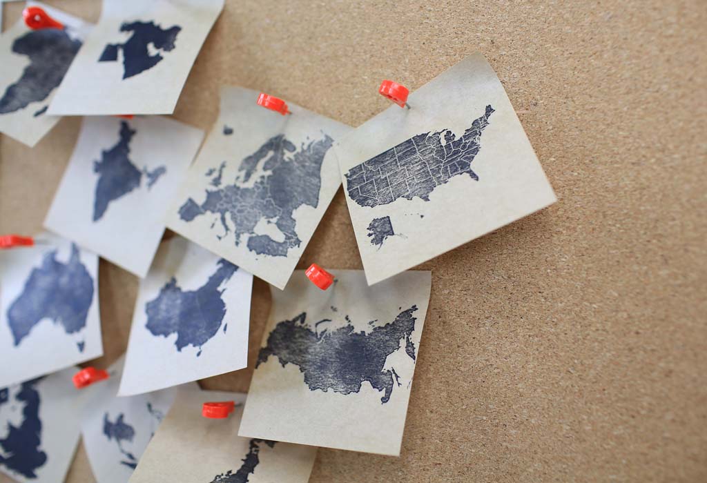 Corcho con imágenes de mapas de varios países sujetas por chinchetas.