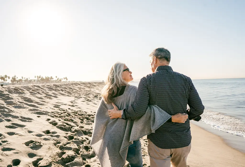 Pareja de espaldas paseando por la playa.