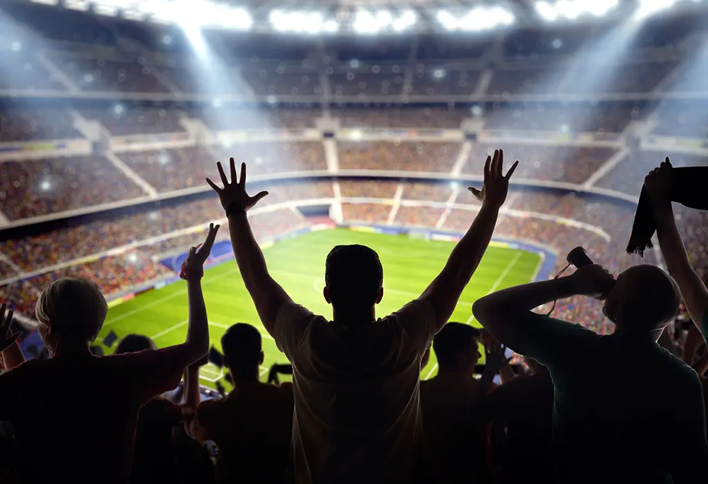 Fan celebrando durante un partido de fútbol en un estadio.