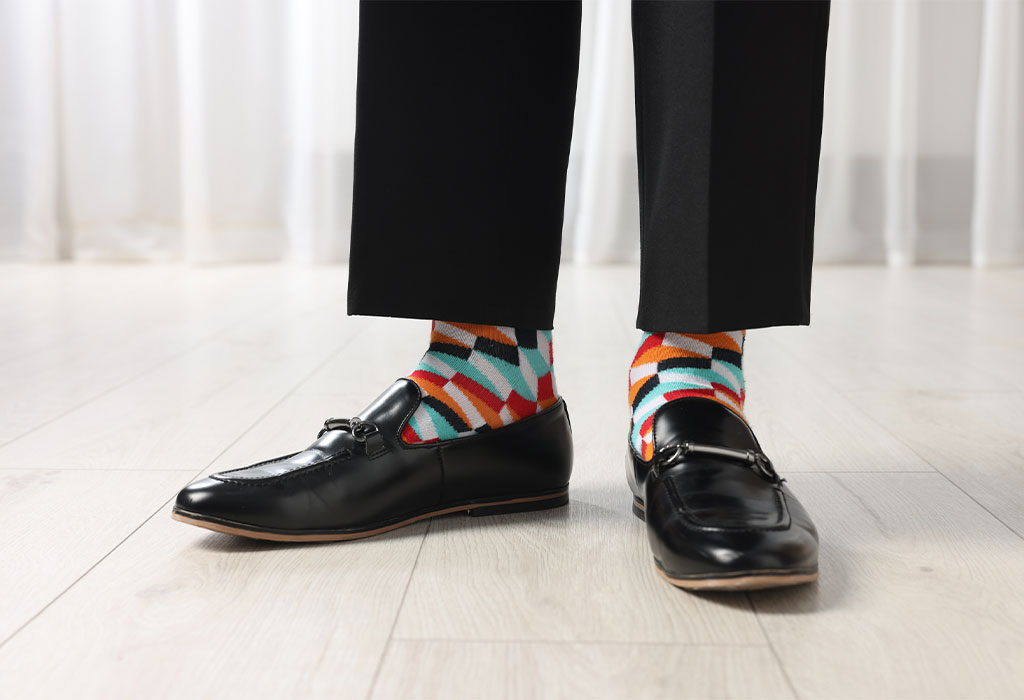 Un hombre viste un traje elegante y lleva calcentines de colores con zapatos formales.