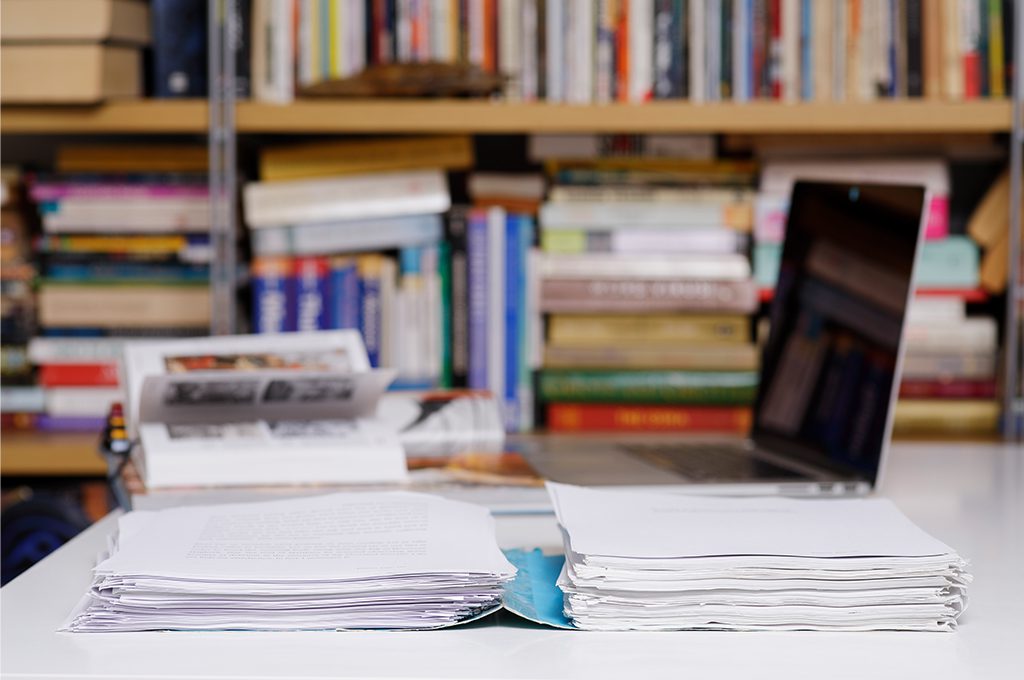 library with computer and a stack of documents