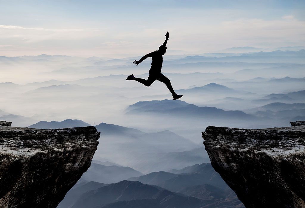 The silhouette of a man jumping a cliff.