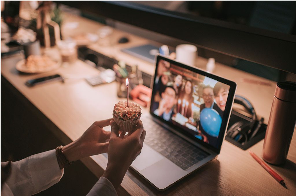 woman working late at the office celebrates her birthday in a videoconference with her team.