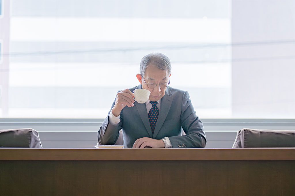 Asian businessman drinks a cup of tea while he waits.