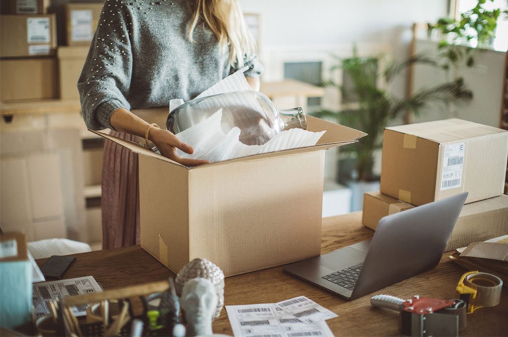 woman packing her product in a box.
