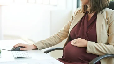 https://www.iese.edu/insight/wp-content/uploads/sites/3/2025/10/pregnant-woman-office-desk.webp