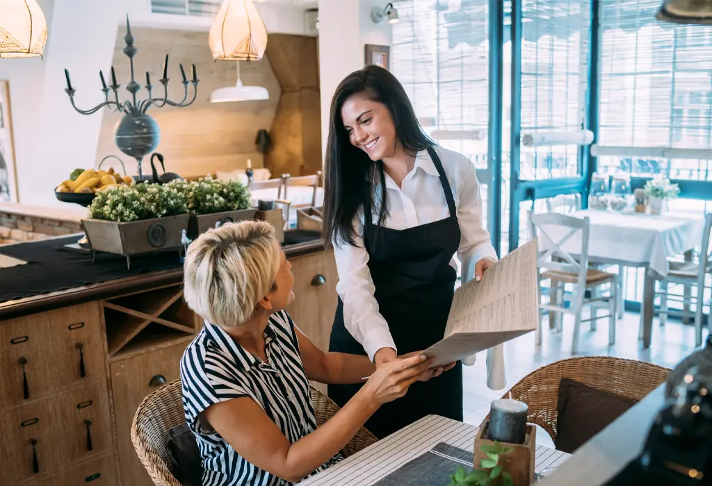 A waitress interacting with a customer at a restaurant.