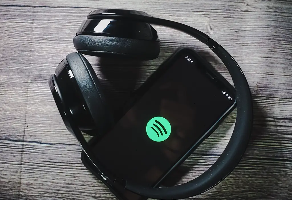 A pair of headphones on a mobile phone with the Spotify logo on its screen.