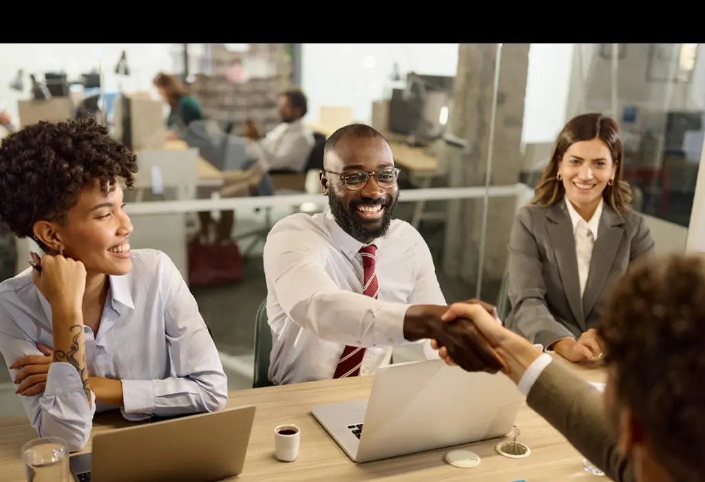 Candidate shaking hands with recruiters during job interview.