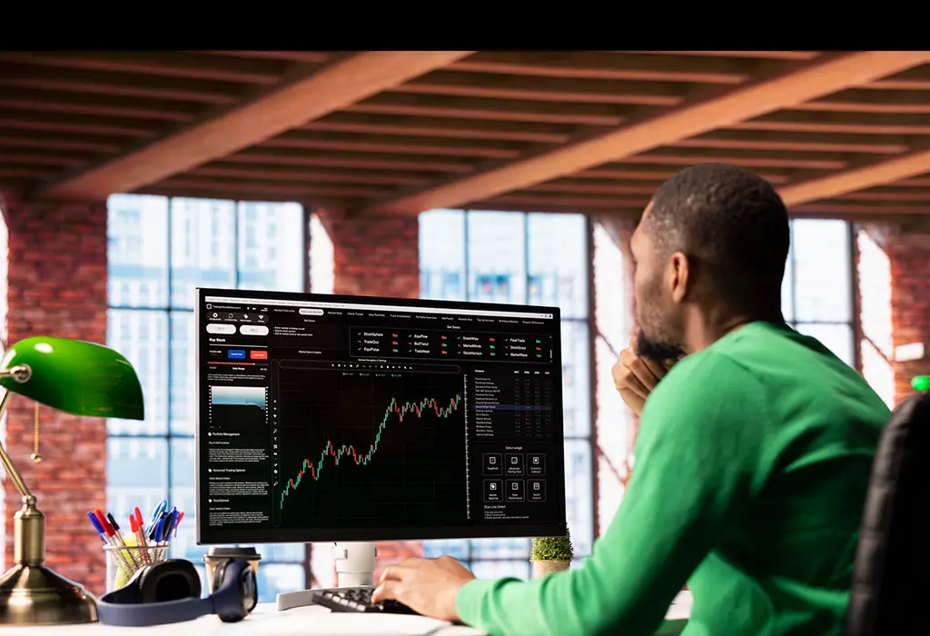 Man sitting in front of a computer looking at some graphics.