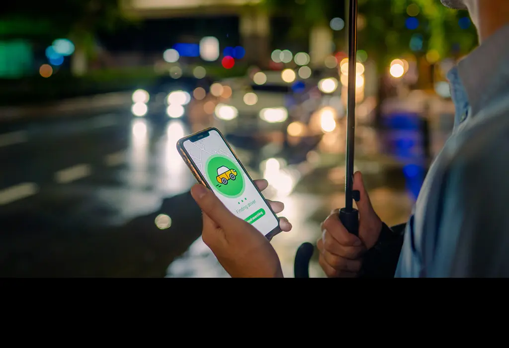 Uber app user holding an umbrella on a rainy night