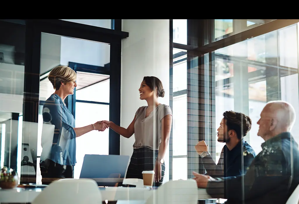 Two women shaking hands in an office room
